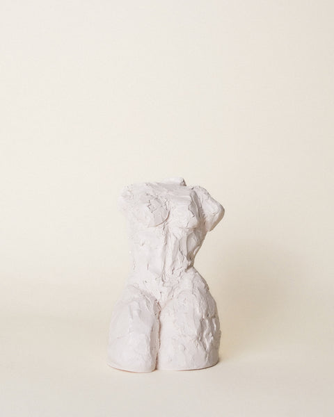 Torso I is a ceramic sculpture of the female form by Artist Dorri Buchholtz. With a textured surface, the body appears to be leaning back, creating a dominant core and strong, proud chest. The natural wax finish is off-white, white a slight pink hue.